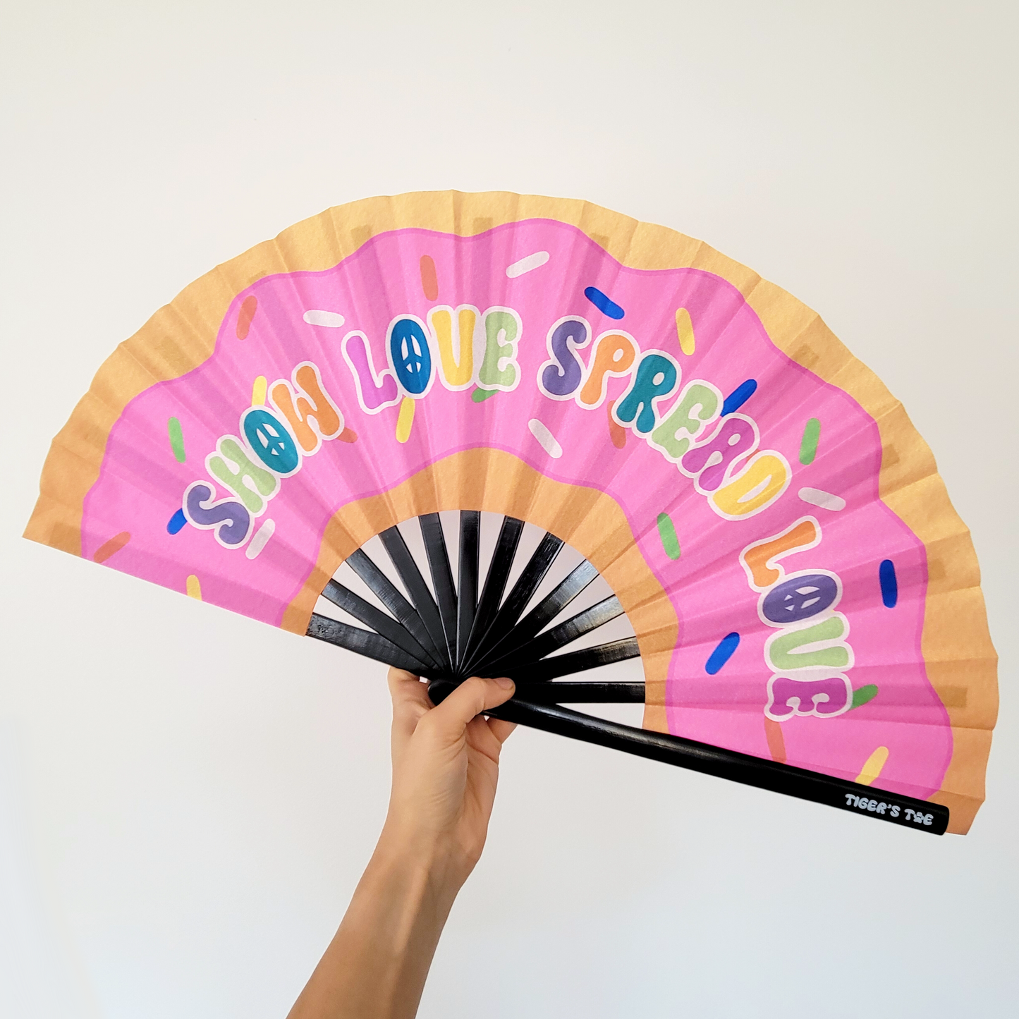 Handheld fan with pink donut design and 'Show Love Spread Love' text on a white background.