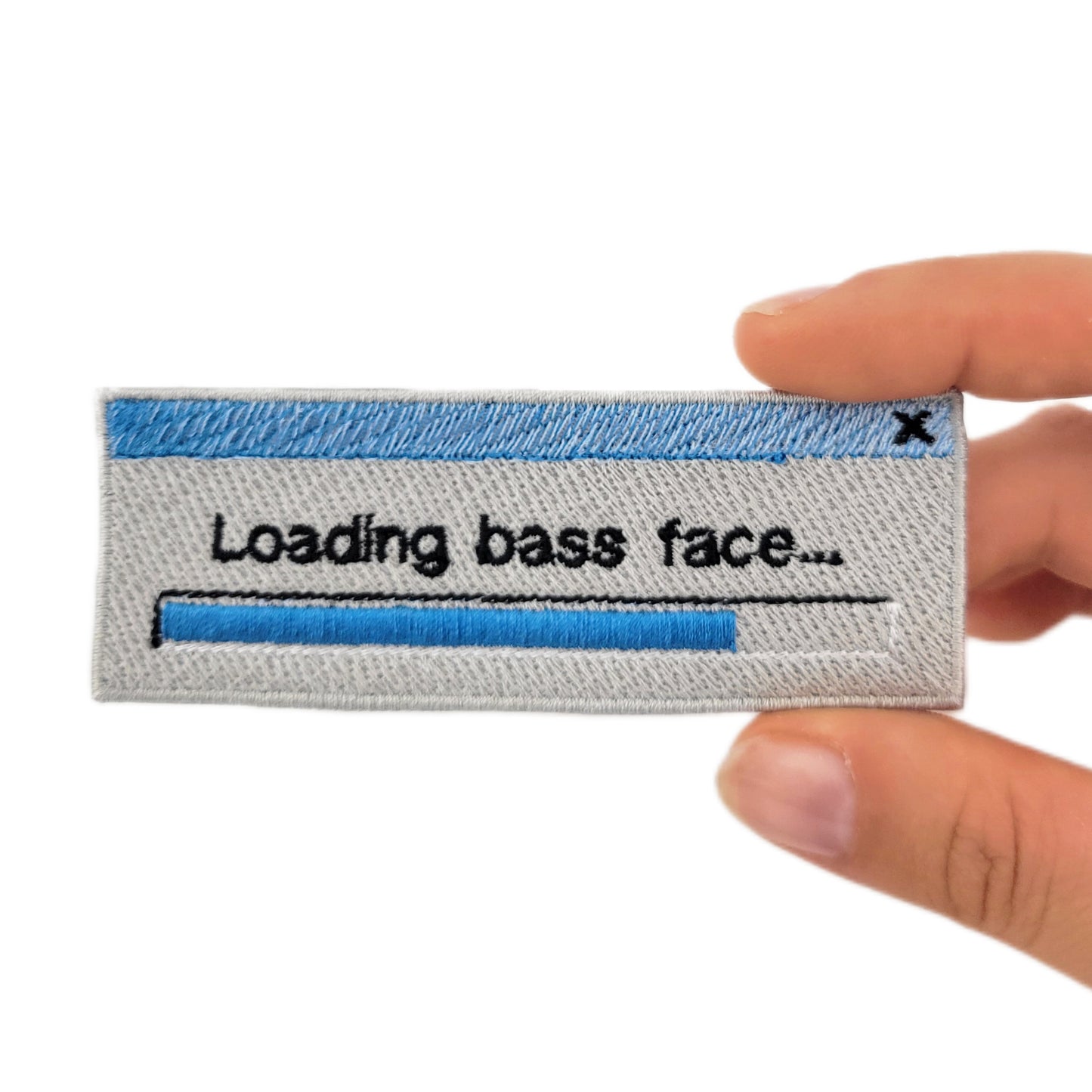 Patch with 'Loading bass face...' text held by a hand on a white background. Made to resemble a retro loading bar window.