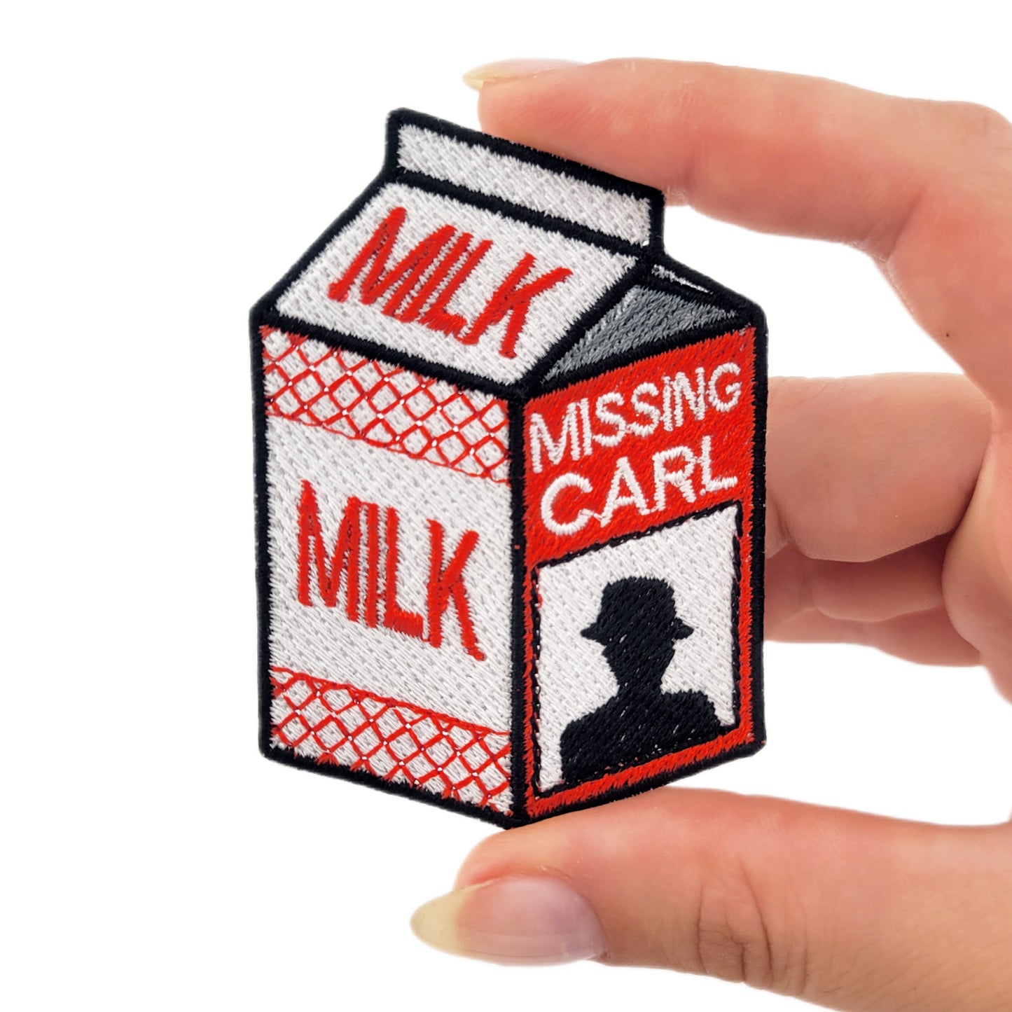 Embroidered patch depicting a milk carton with a man's silhouette on the side, the text reads "MISSING CARL"
