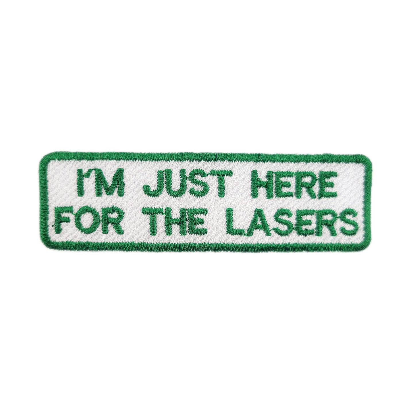 Embroidered patch with text 'I'm just here for the lasers' written in green text on a white background