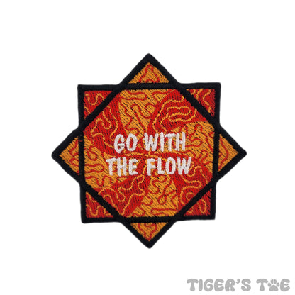 Embroidered patch of a red and orange flow star with decorative swirls. The center of the flow star reads "GO WITH THE FLOW" in white text.