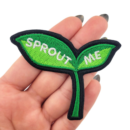 Green leaf-shaped patch with 'SPROUT ME' text held in a hand against a white background
