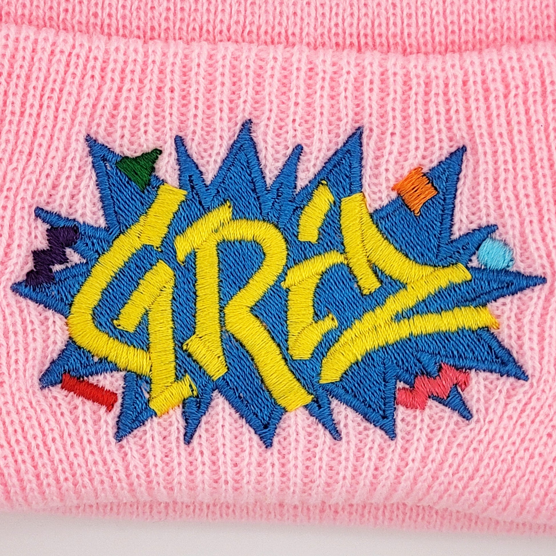 Pink beanie with colorful 'GRIZ' embroidery, close-up