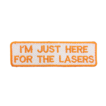 Embroidered patch with text 'I'm just here for the lasers' written in orange text on a white background