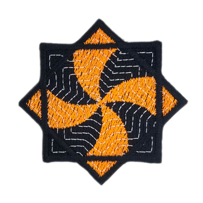 Embroidered patch of an orange and black flow star on a white background