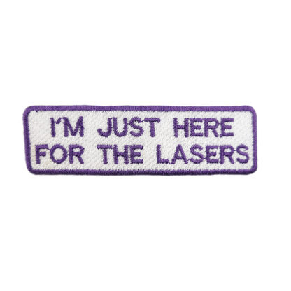 Embroidered patch with text 'I'm just here for the lasers' written in purple text on a white background
