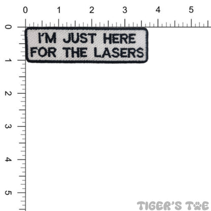 Embroidered patch with 'I'm just here for the lasers' text on a white background with a ruler for scale.